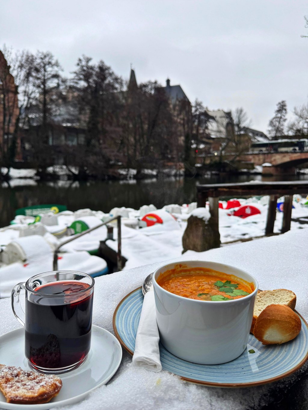 Glühwein und heiße Tomatensuppe auf der Terrasse mit Blick auf verschneite Marburger Altstadt und Tretboote